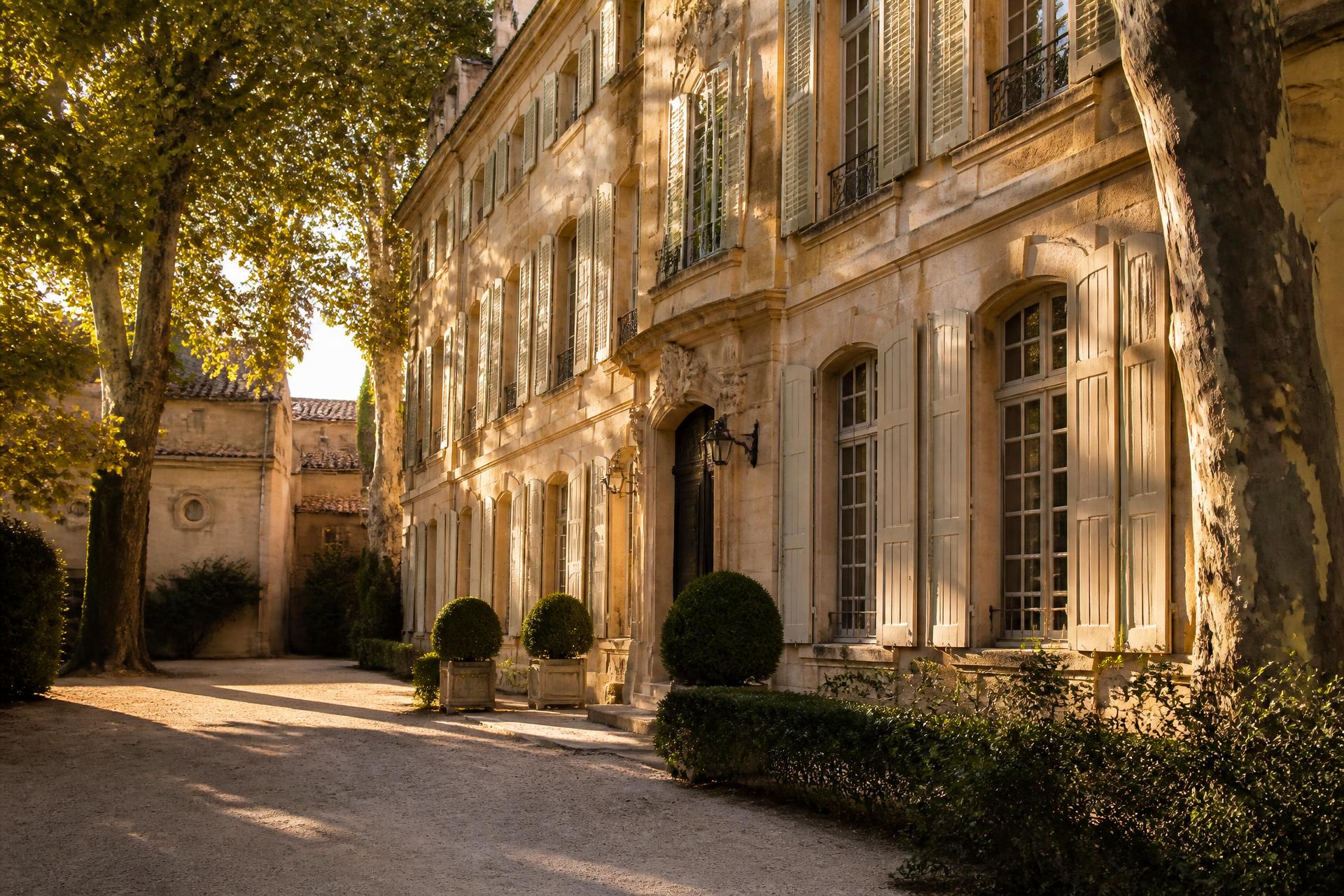 Façade d'un hôtel particulier en pierre à Aix-en-Provence baignée de lumière dorée